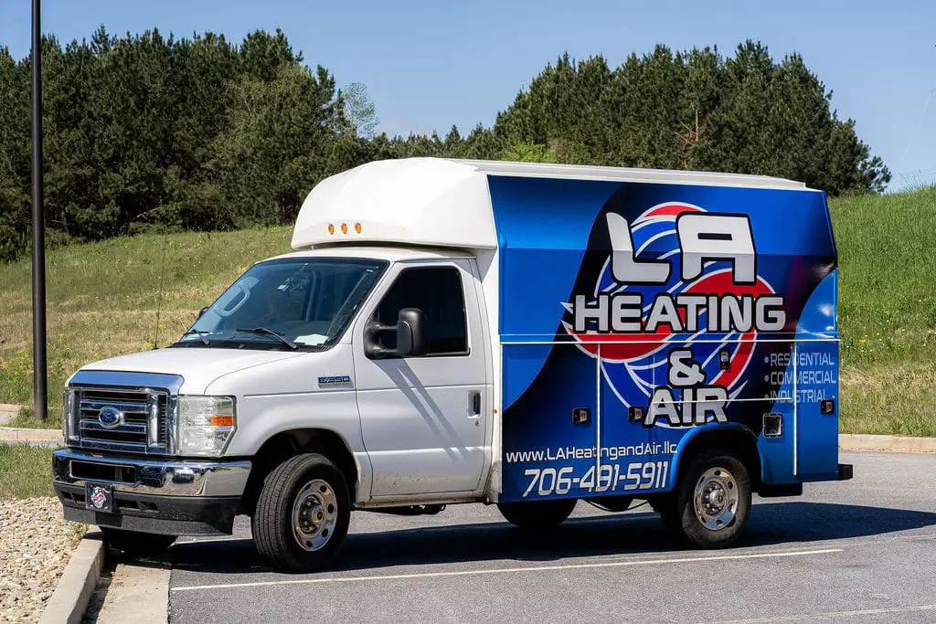 LA Heating and Air LLC service van on road with company logo and contact information